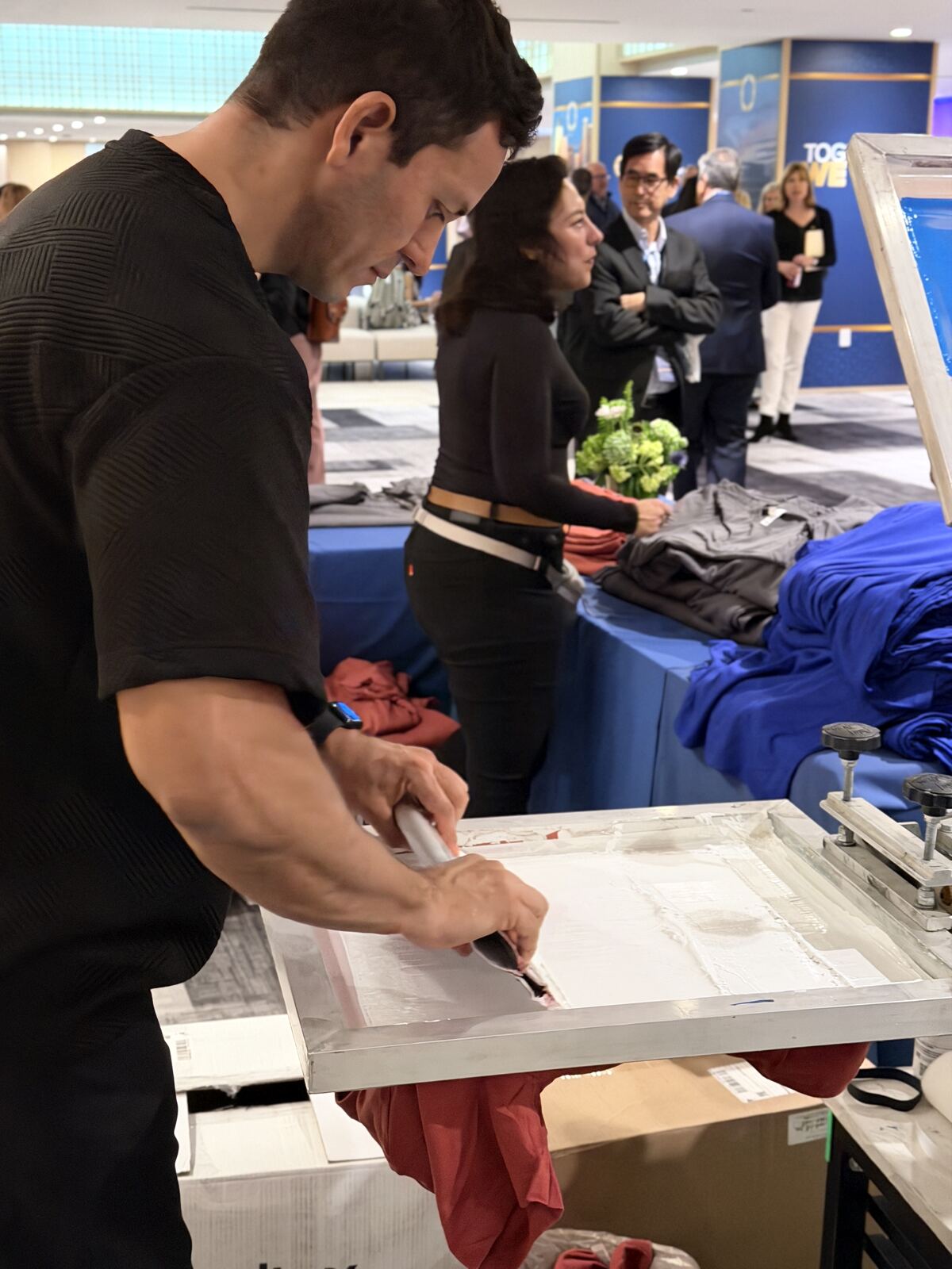 Corporate attendees reviewing screen-printed apparel samples at a trade show booth